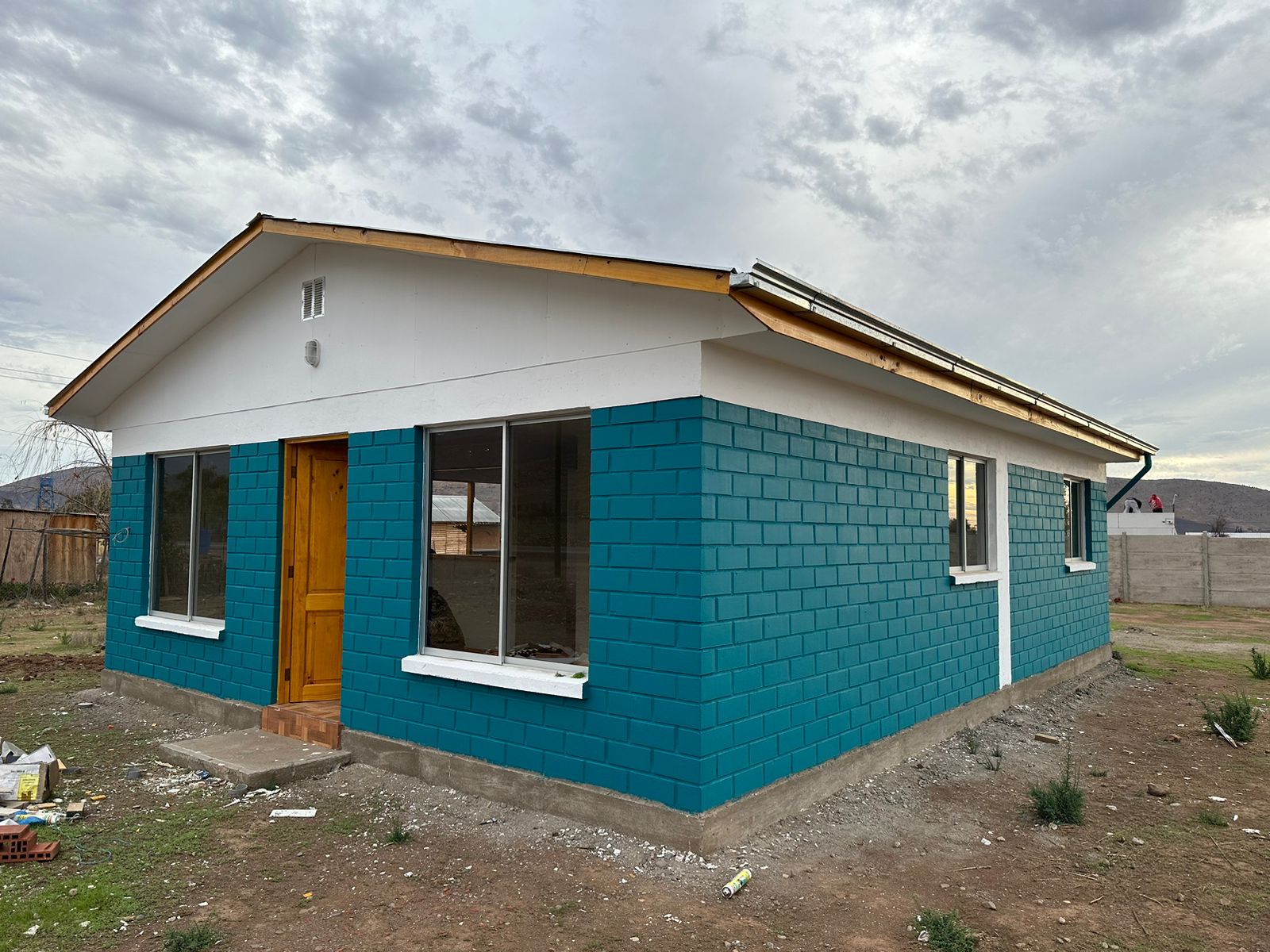 Vivienda de fachada turquesa en etapa de terminaciones